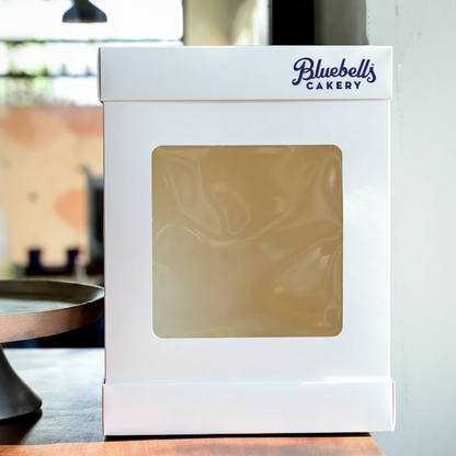 White cake box with window featuring 'Bluebell's Cakery' branding on a blurred background.